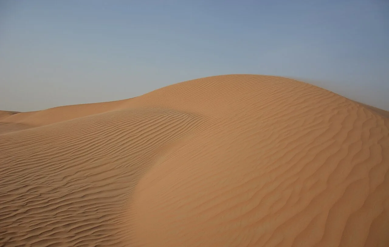 كثبان رملية ذهبية تحت سماء صافية في الإمارات